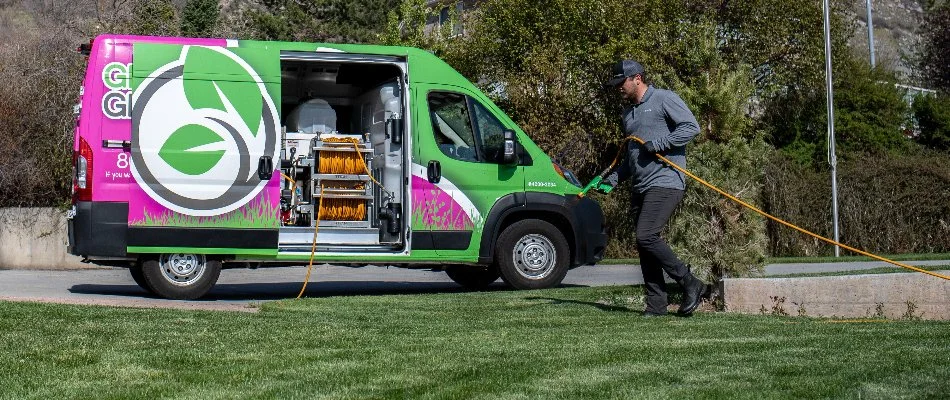 Worker in Midway, UT, spraying liquid fertilizer on grass.